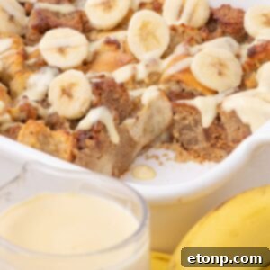 Banana Bread Pudding in a casserole dish with a glass of milk and bananas in front of the pan