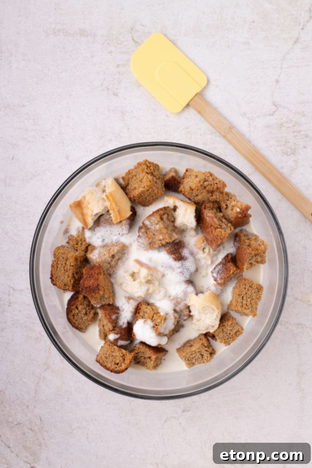 bread with the custard mixture in a glass bowl on table 