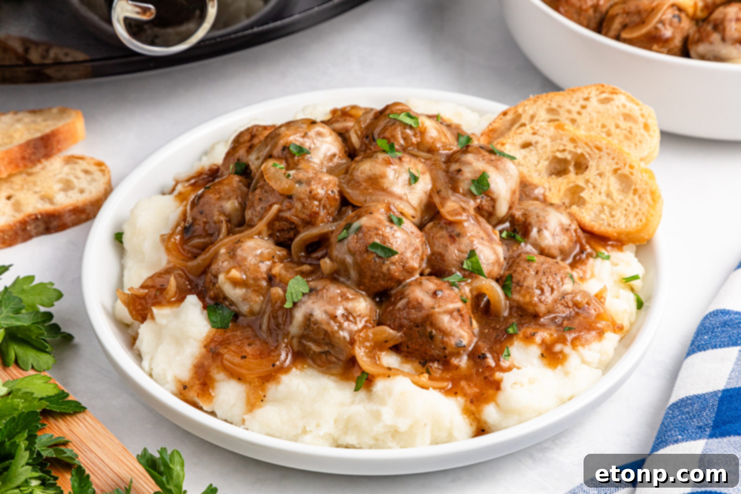 Crock Pot French Onion Meatballs on a white plate over mashed potatoes