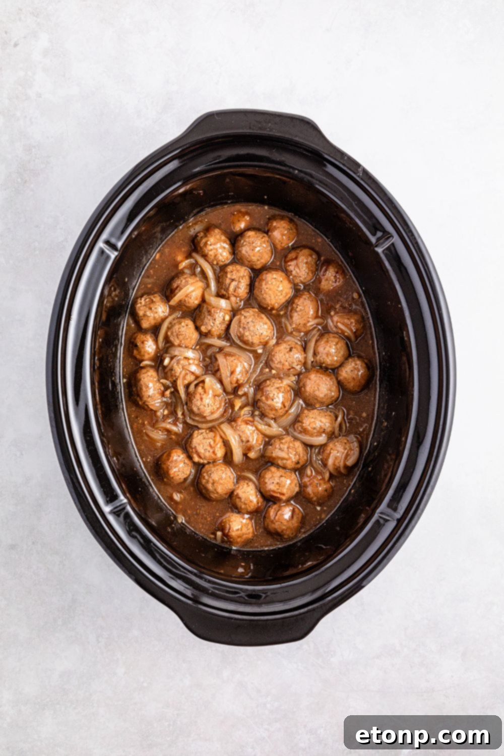 meatballs smothered in a French onion flavored sauce in a crockpot on table 