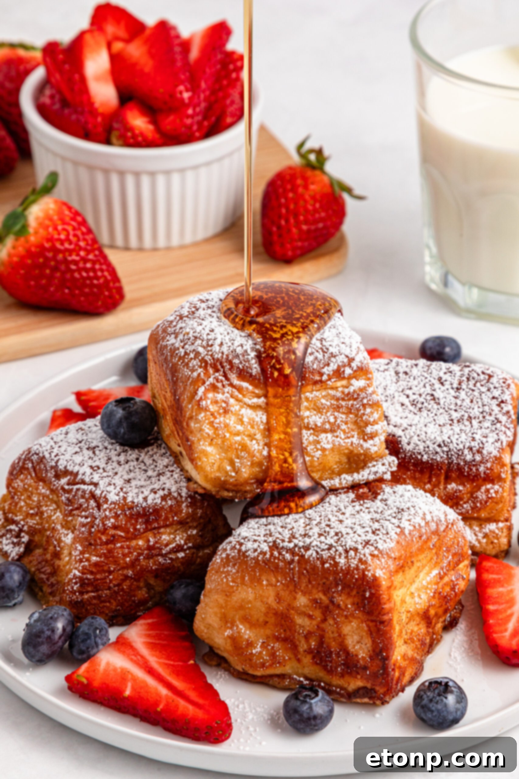 syrup being poured on top of the Hawaiian Roll French Toast, glistening in the light