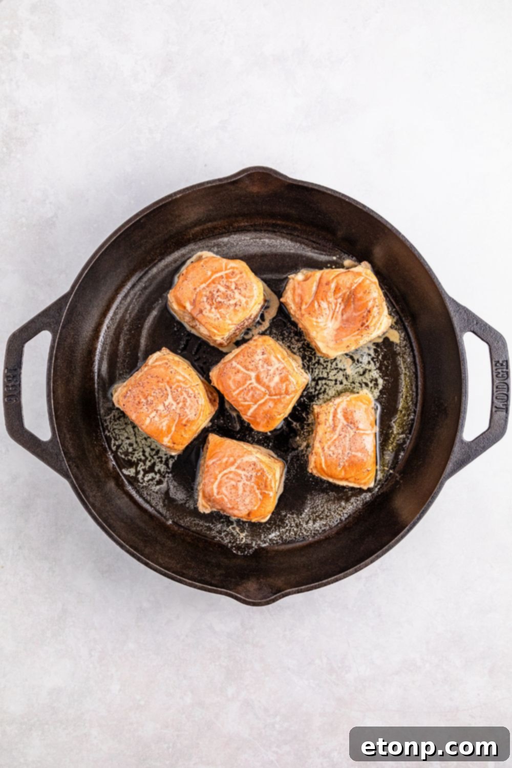 Hawaiian Roll French Toast sizzling and cooking in a cast iron skillet, turning golden