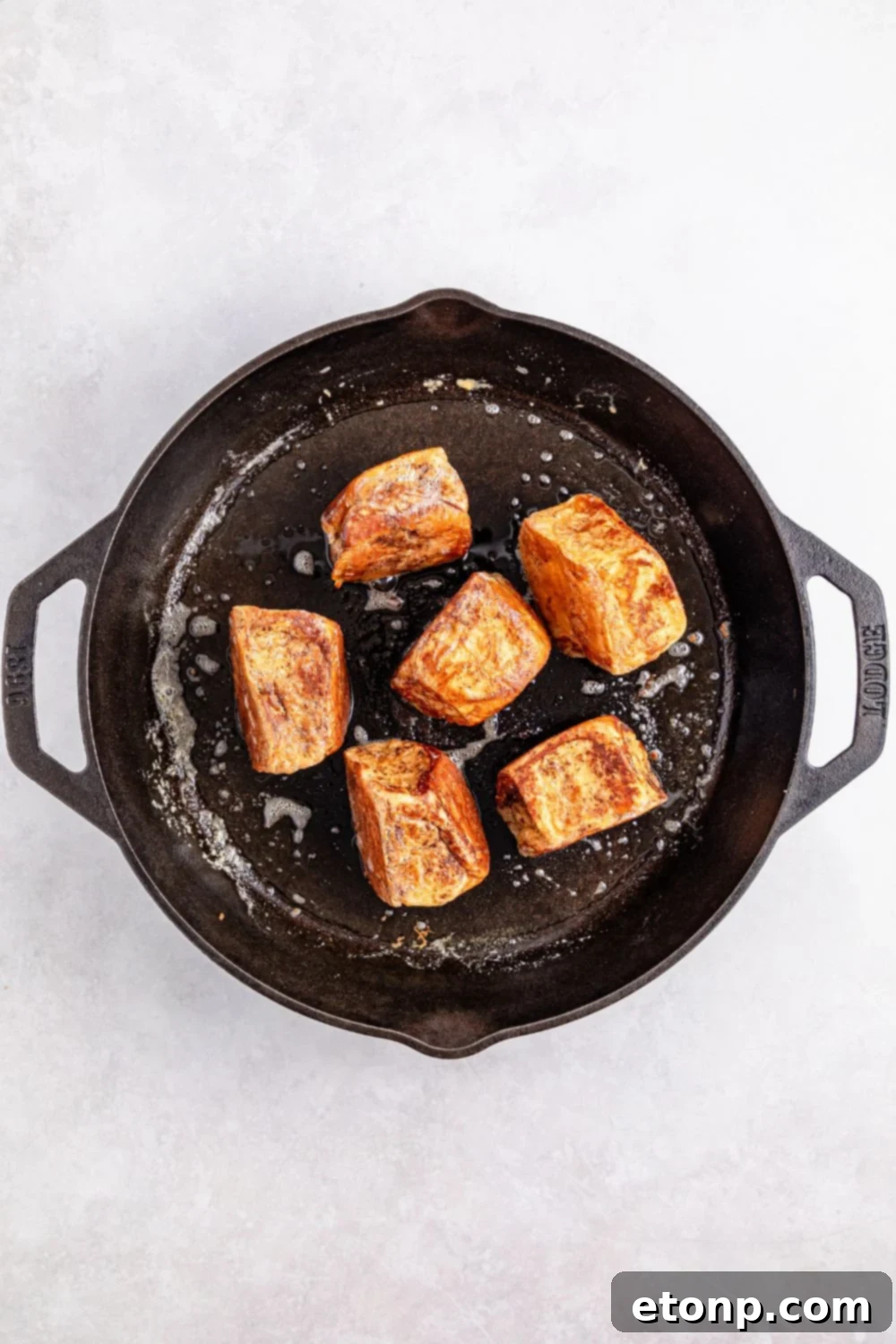 Hawaiian Roll French Toast pieces beautifully searing in a cast iron skillet, achieving a perfect crust