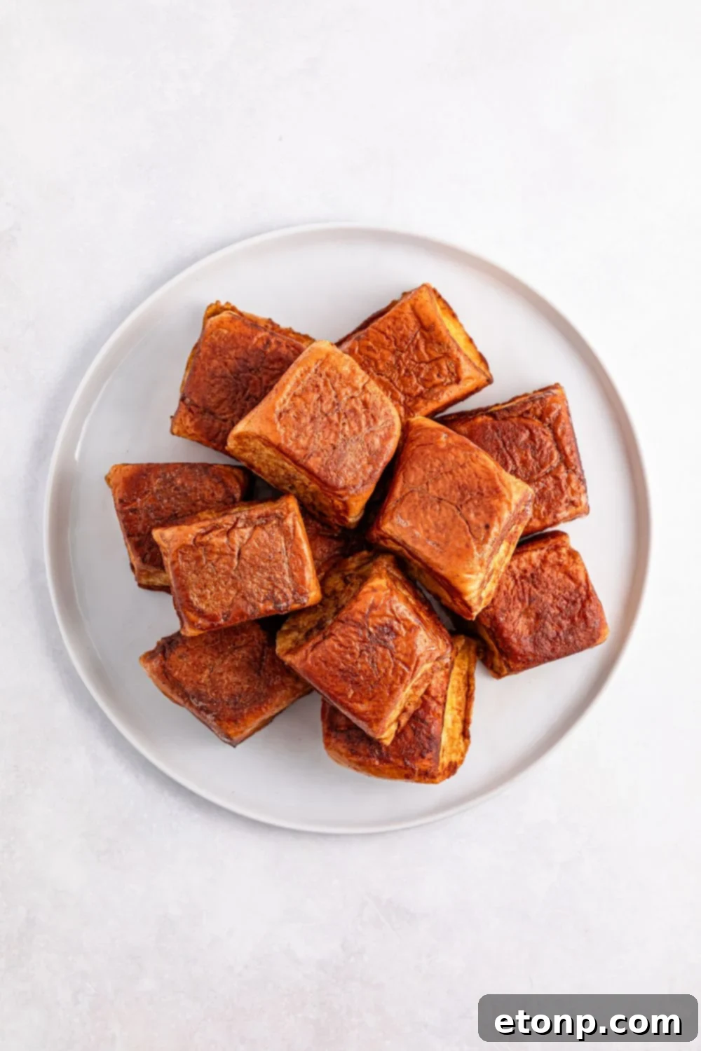 a stack of perfectly cooked Hawaiian Roll French Toast on a white plate, ready to be served