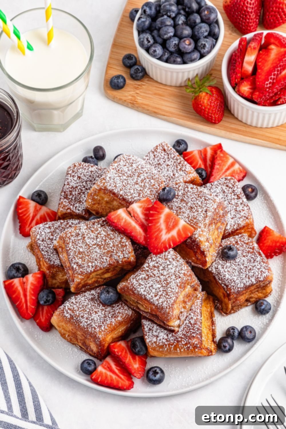 individual Hawaiian Roll French Toast pieces arranged artfully on a plate with scattered fresh berries