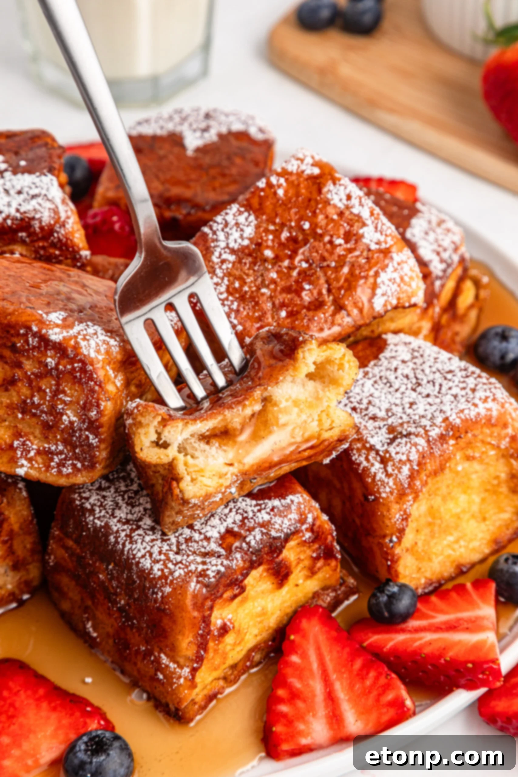 golden Hawaiian Roll French Toast with a fork lifting a piece, covered in syrup