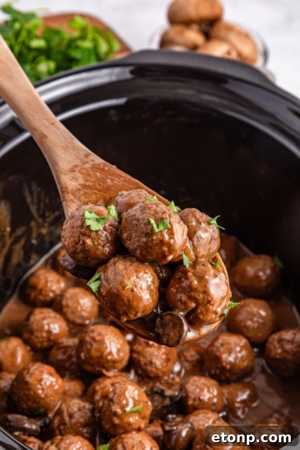Comforting Slow Cooker Salisbury Steak Meatballs 12 Crock Pot Salisbury Steak Meatballs in a crockpot on table with a wooden spoon with some meatballs being lifted out of the crockpot