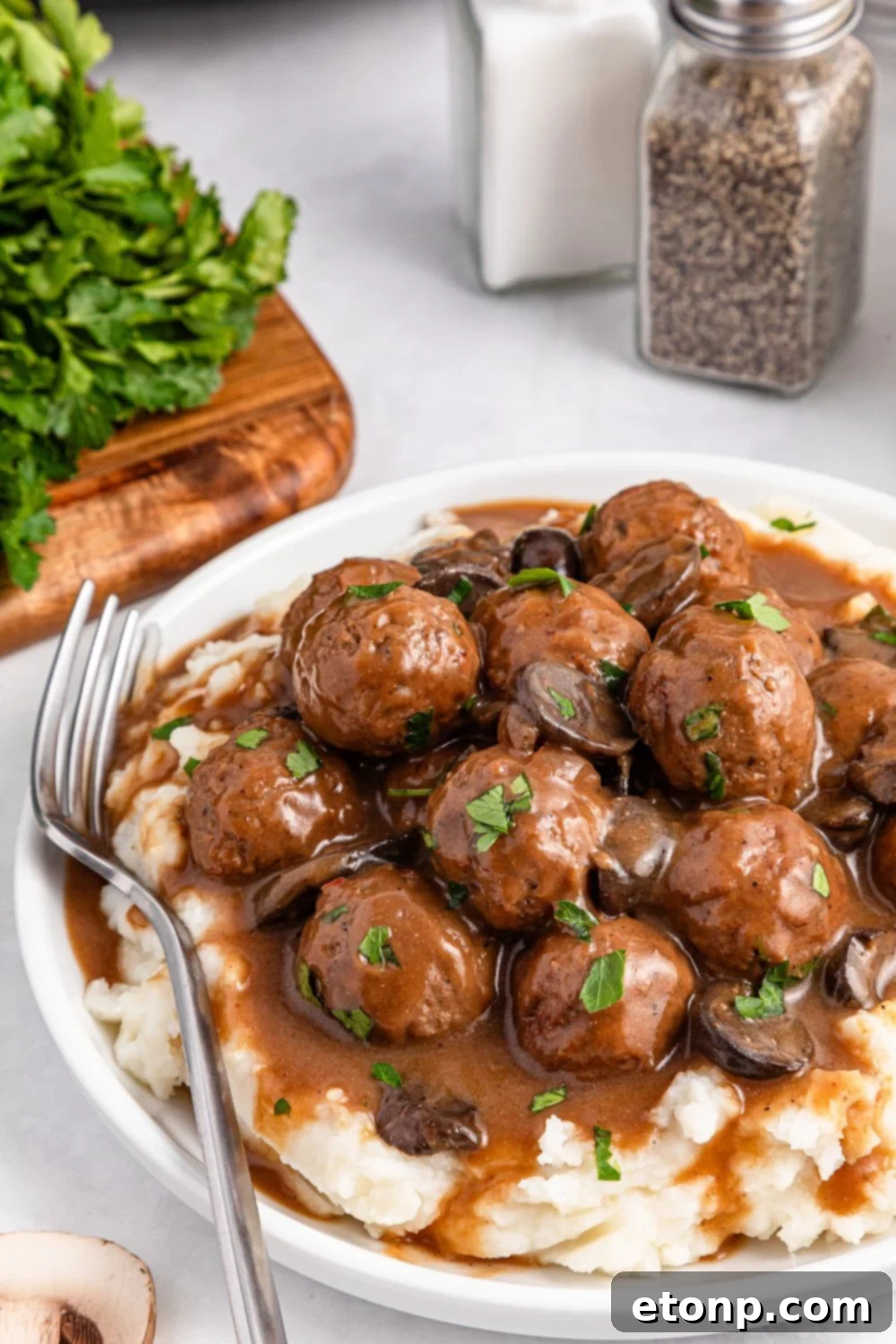 Comforting Slow Cooker Salisbury Steak Meatballs 14 Salisbury Steak Meatballs with mashed potatoes under them on a plate with a fork to the side