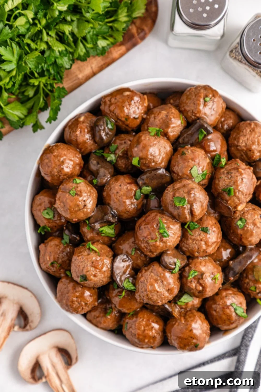 Comforting Slow Cooker Salisbury Steak Meatballs 5 Crock Pot Salisbury Steak Meatballs in a bowl on table with parsley and fresh mushrooms by the bowl on table