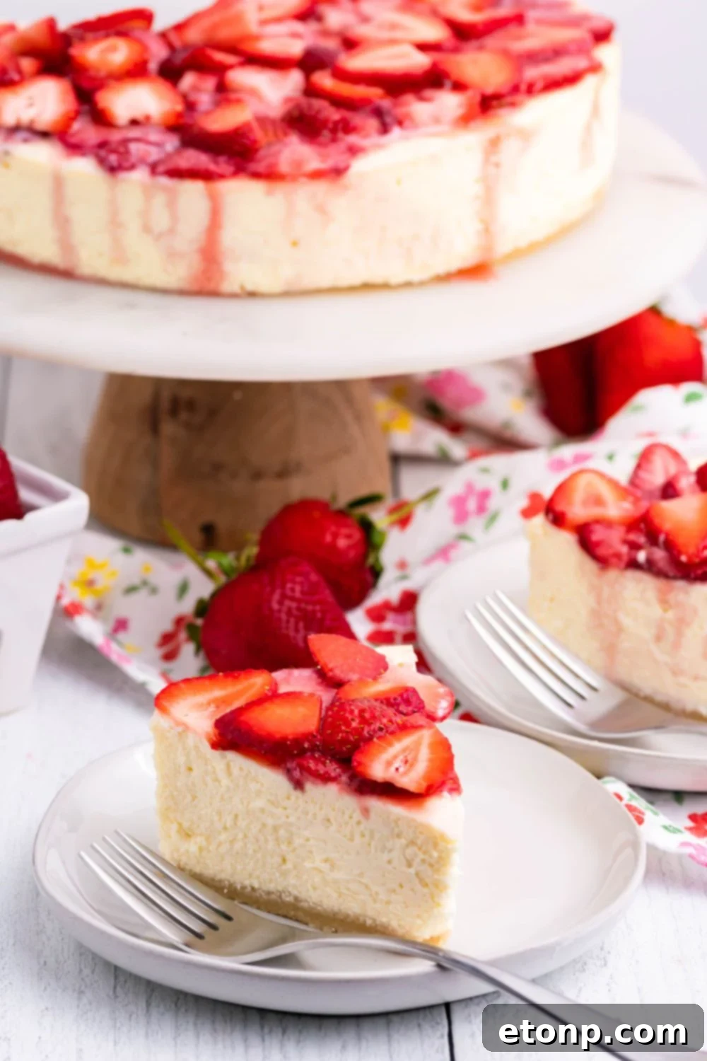 Keto Cheesecake on a pie platter and slices of cheesecake on small plates with berries on top 
