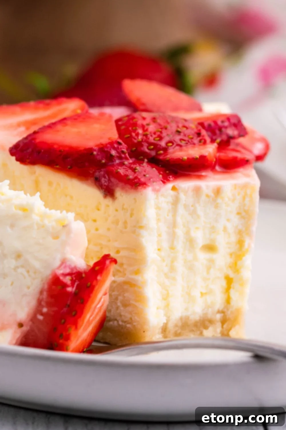 Slice of Keto Cheesecake on a plate with a bite being placed on fork to show the dense texture of cheesecake 