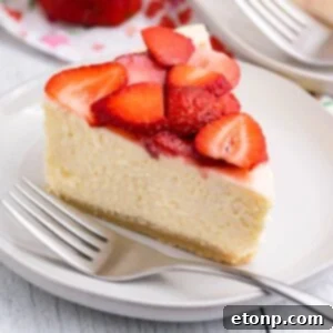 slice of keto cheesecake on a plate topped with strawberries and fork on the side of plate