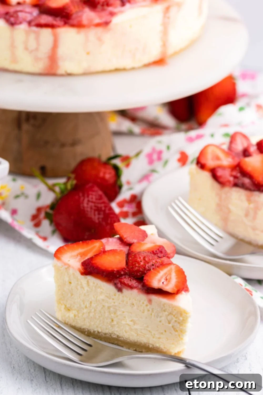 Keto Cheesecake on a platter with slice of cheesecake on the table around it 