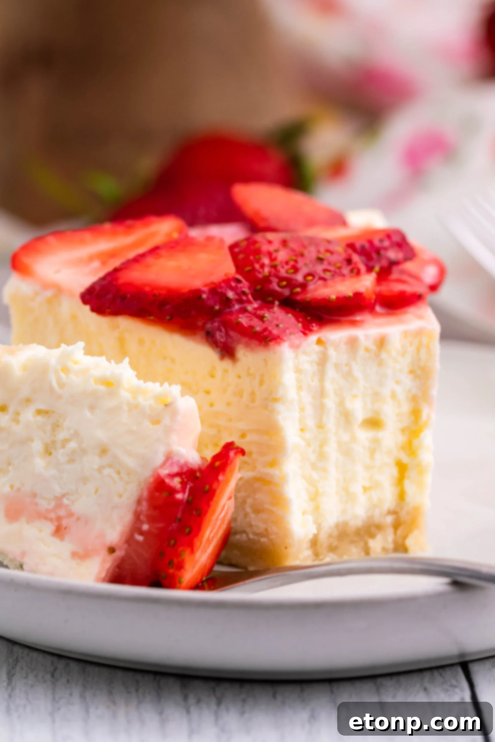 Keto cheesecake on a white plate with strawberries on top
