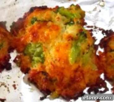 A child's hand reaching for a freshly baked cheesy broccoli patty