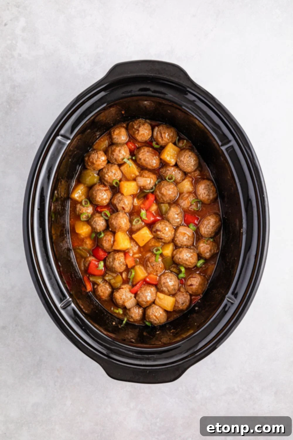 Crock Pot Sweet And Sour Meatballs mixed up in a crockpot 