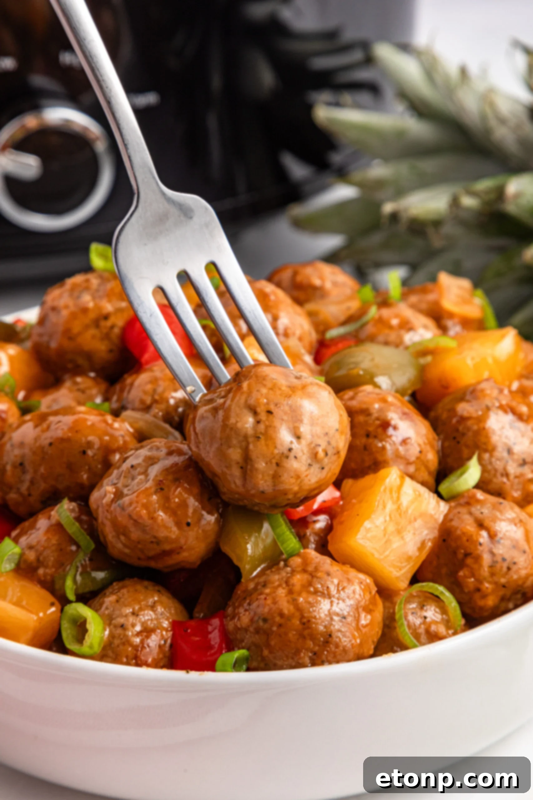 Crock Pot Sweet And Sour Meatballs in a bowl with a fork in one of the meatballs 
