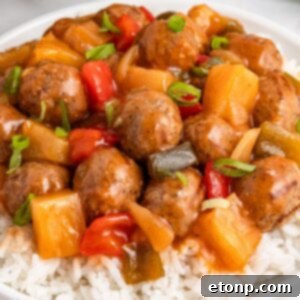 Crock Pot Sweet And Sour Meatballs piled on a bed of rice on plate