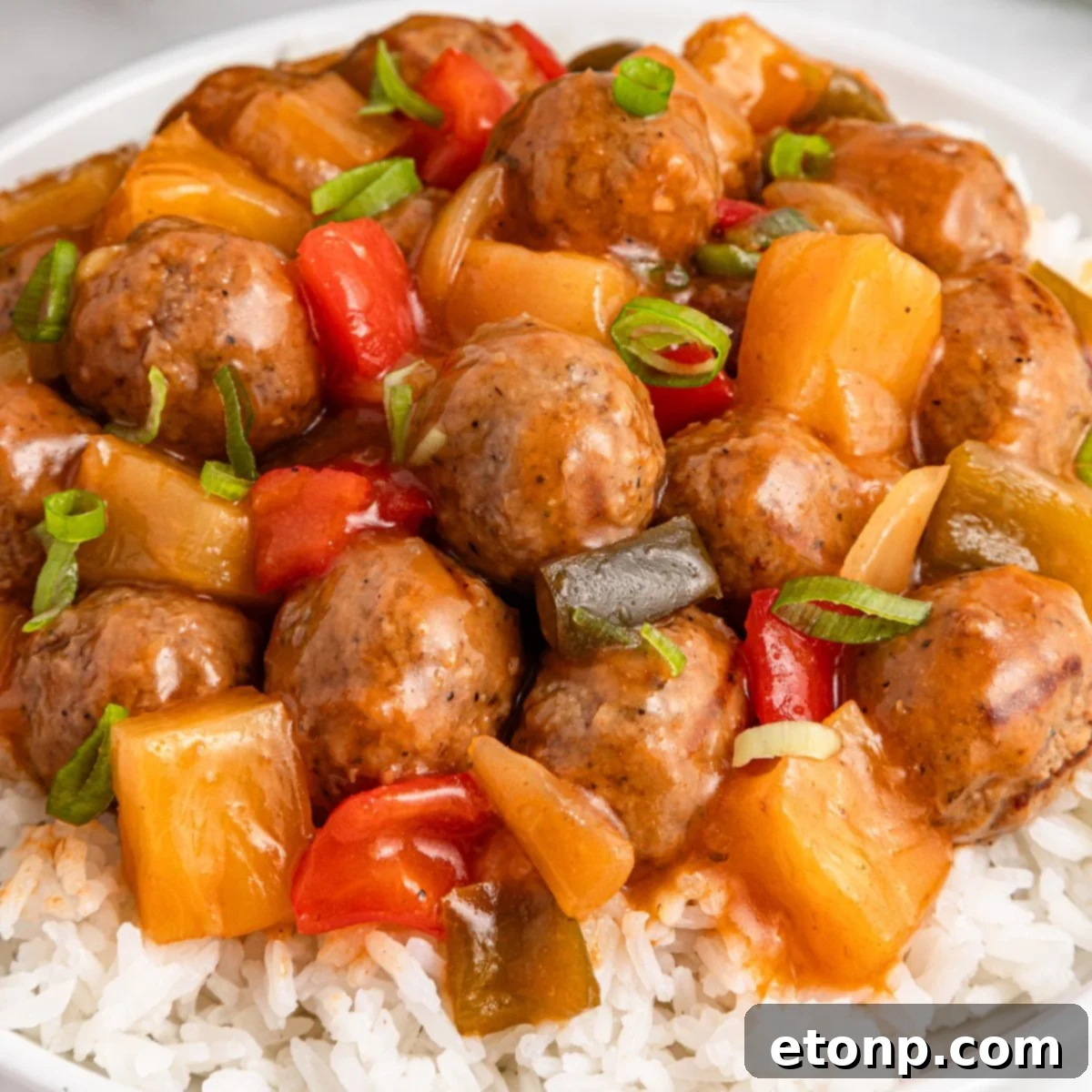 Crock Pot Sweet And Sour Meatballs piled on a bed of rice on plate 