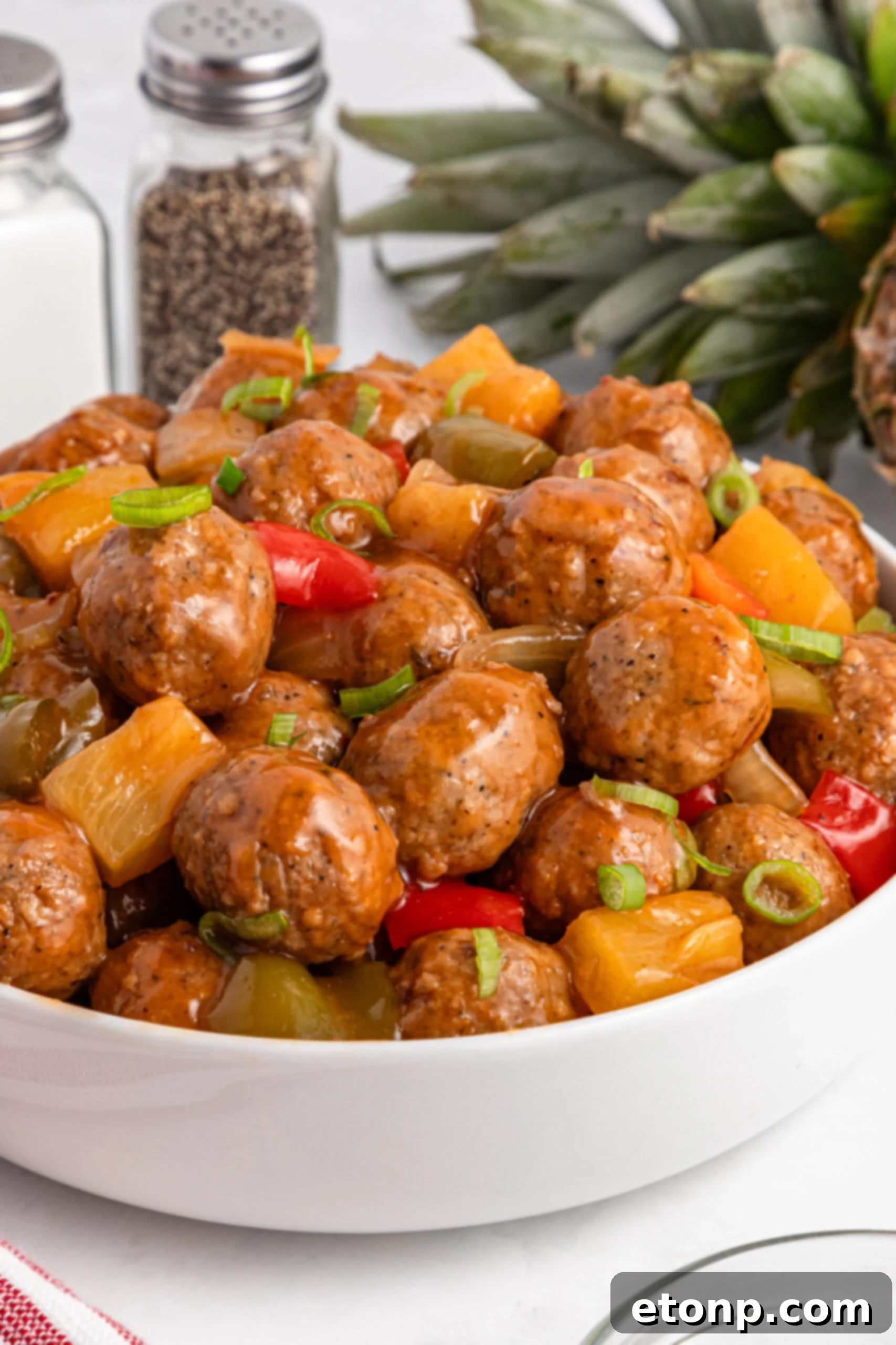 Crock Pot Sweet And Sour Meatballs piled on a bed of rice on plate 