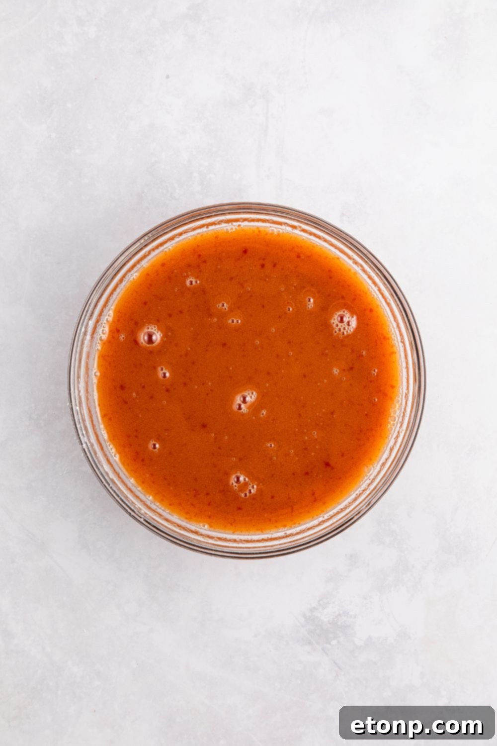 sweet and sour meatball sauce sitting on table in a glass bowl 