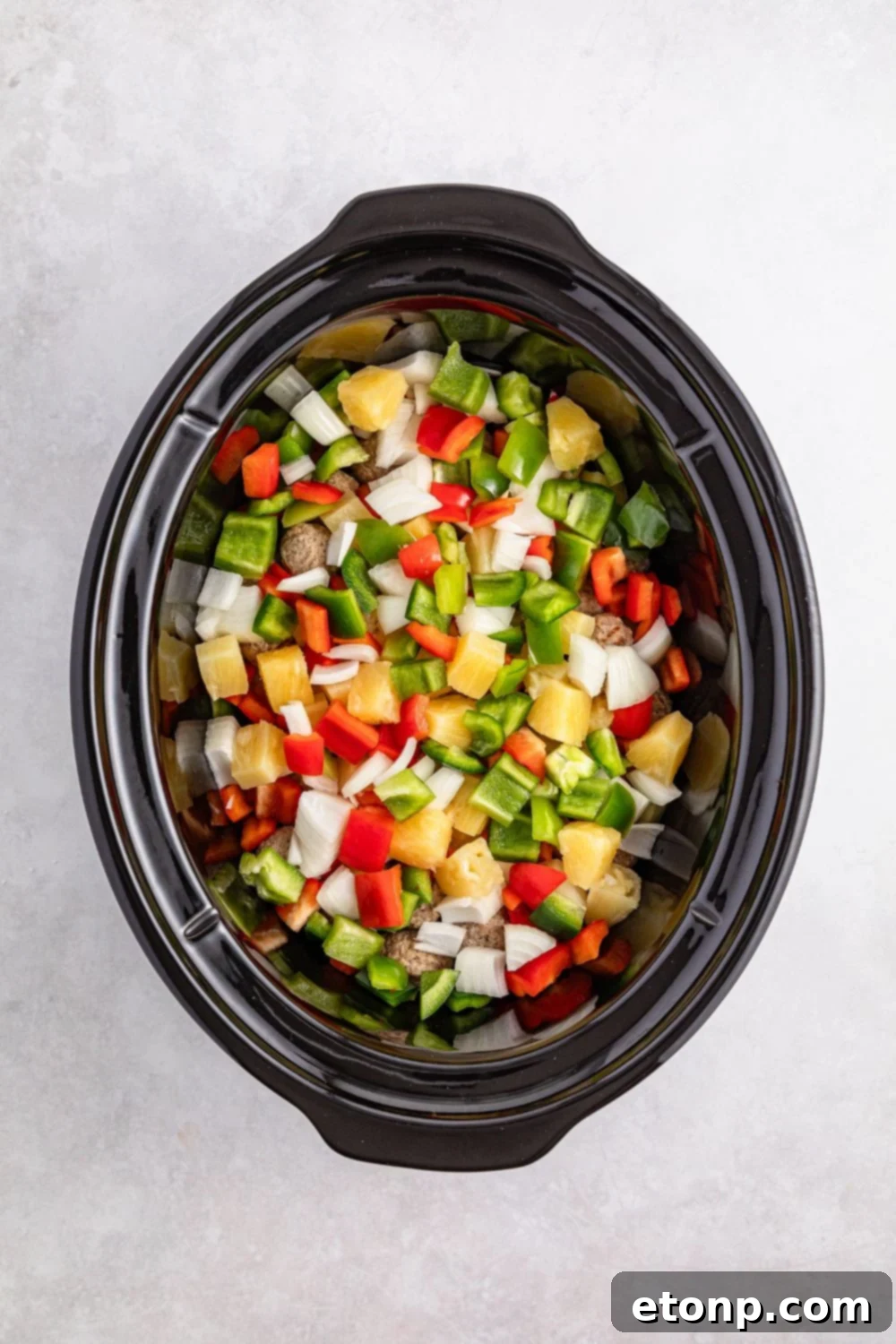 diced peppers and onions in a slow cooker on table for the Crock Pot Sweet And Sour Meatball recipe 