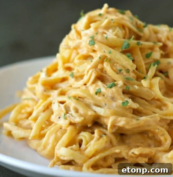 Creamy cheesy buffalo chicken pasta dish garnished with green onions