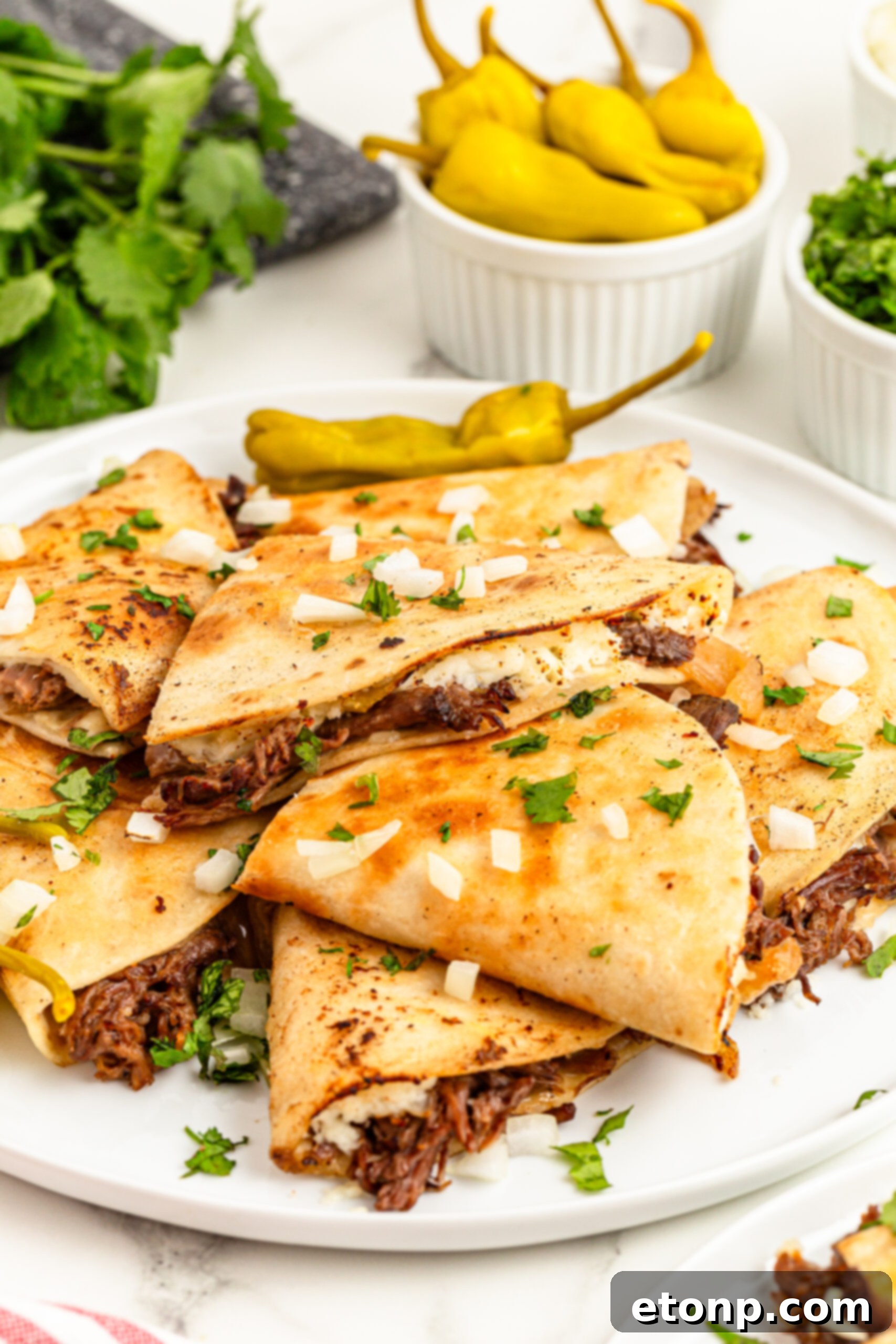 The Mississippi Pot Roast Remix 6 Mississippi Pot Roast Quesadillas piled on a plate with a bowl of peppers in the background