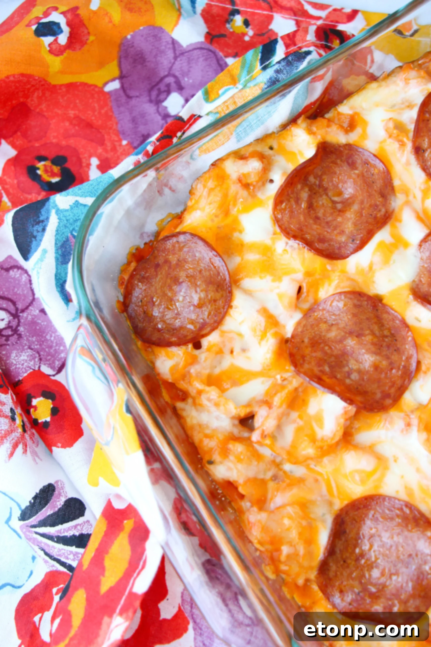 Hands mixing pasta sauce, cream cheese, and pepperoni.