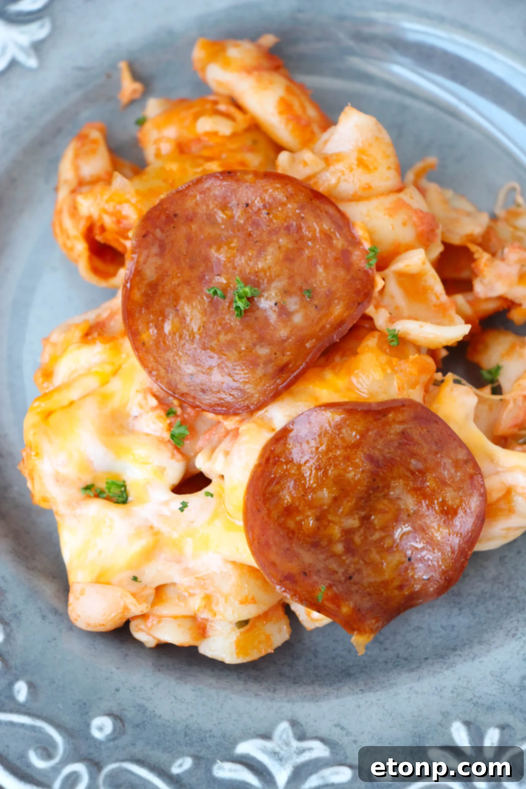 Close-up of a serving of pepperoni pizza pasta bake on a plate.