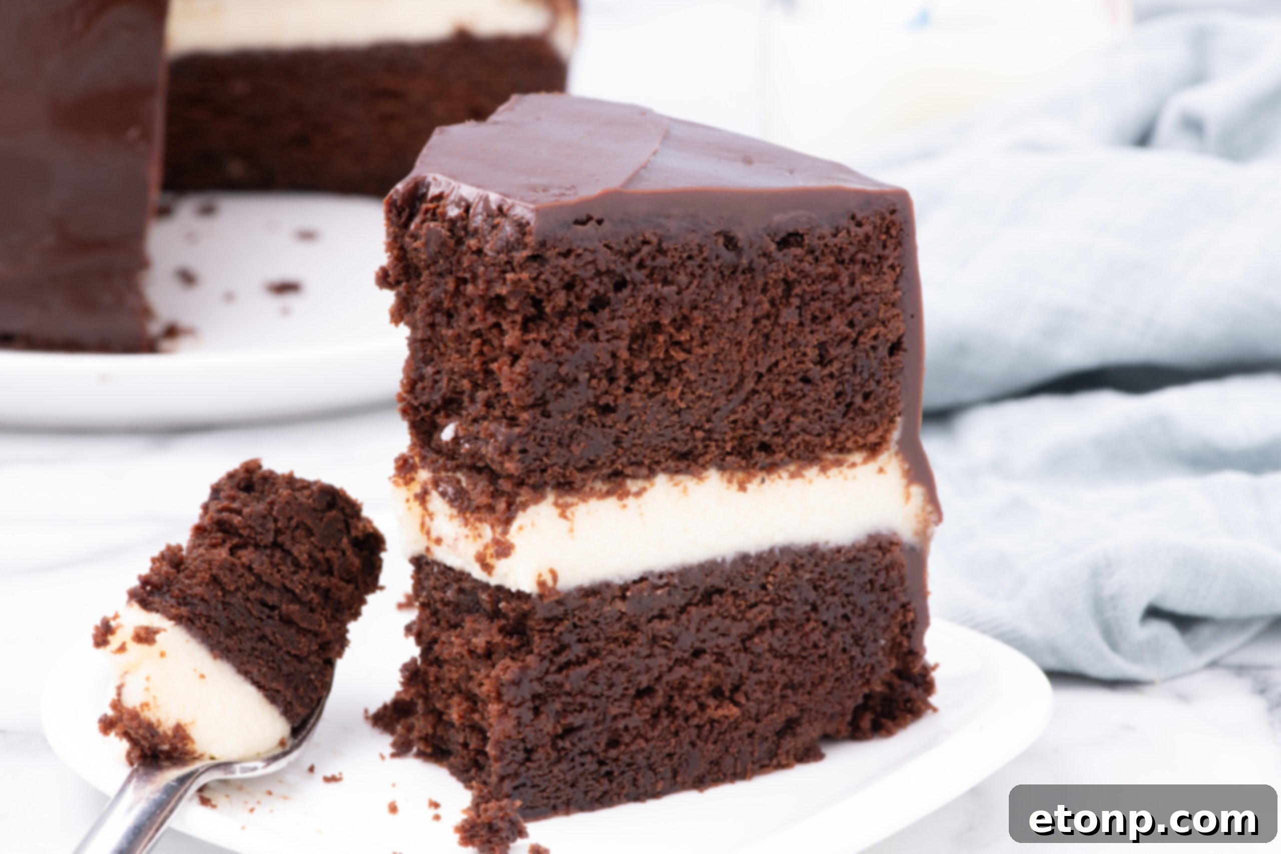Slice of Ding Dong Cake on a white plate with a fork holding a bite 