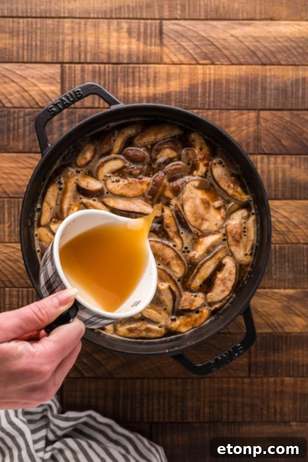 Chicken broth being carefully poured into a pot, beginning the preparation of P.F. Chang's Hot and Sour Soup