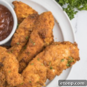 Air Fryer Chicken Tenders on a white plate with a small cup of BBQ sauce on the side