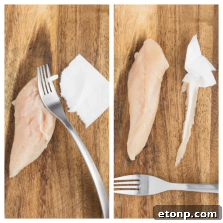 Raw Air Fryer Chicken Tender having the tendon removed with a fork