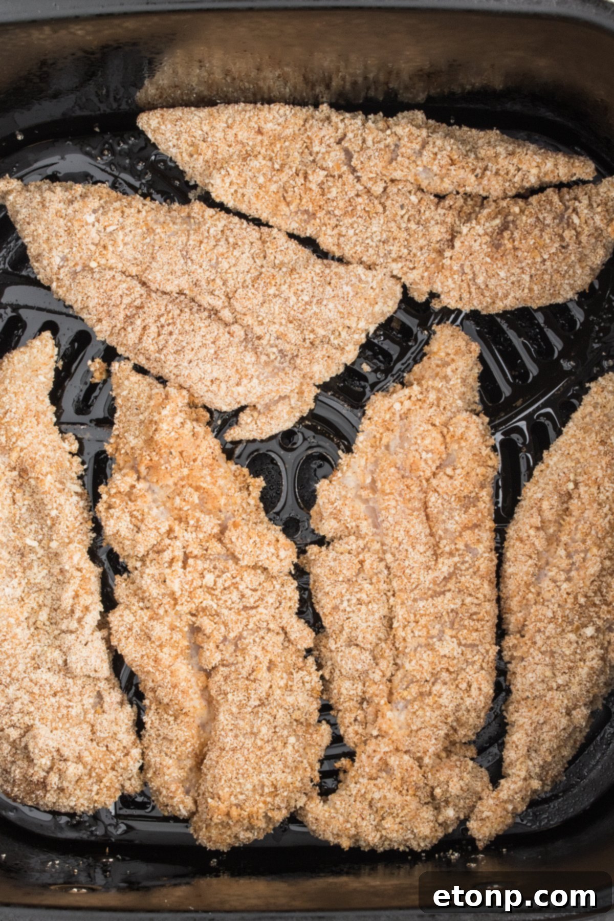 Air Fryer Chicken Tenders uncooked arranged in the air fryer basket