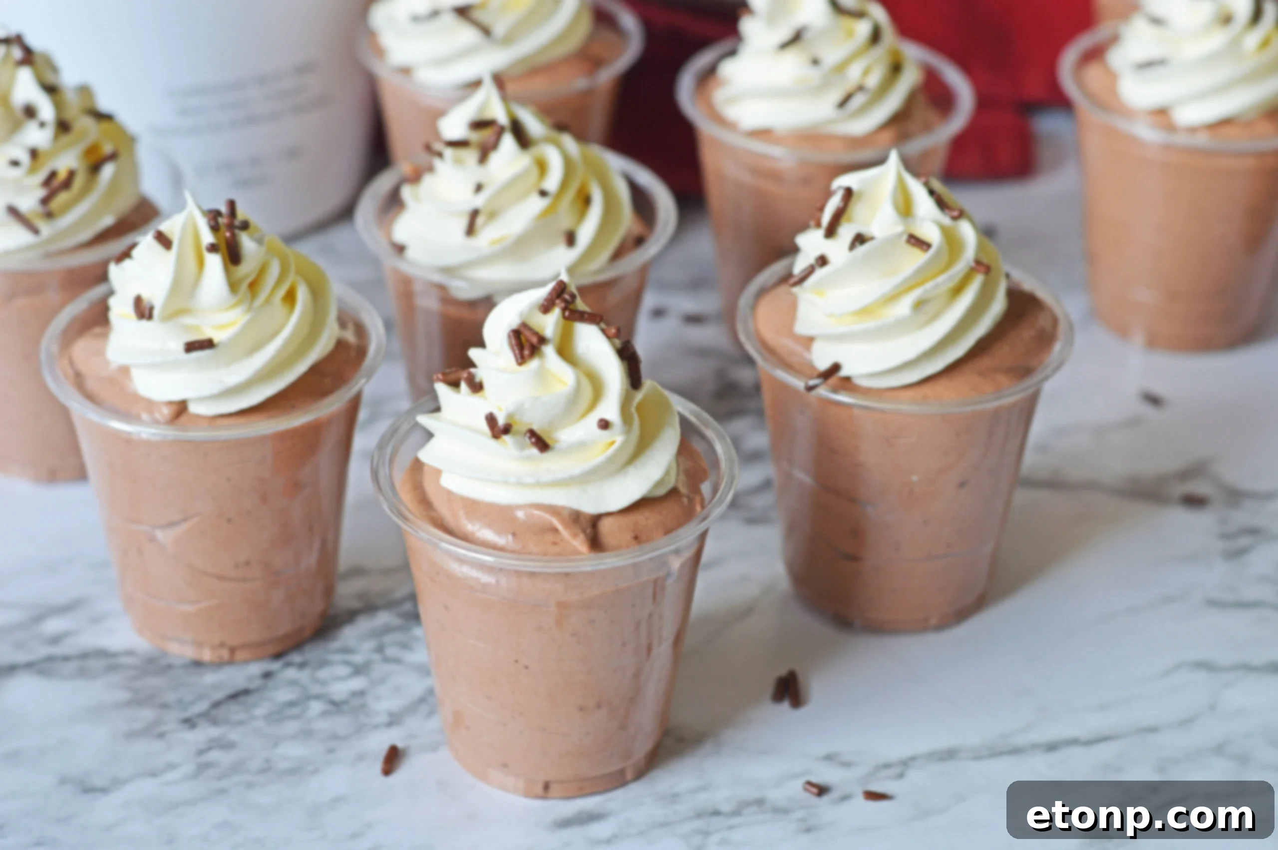 Decadent Chocolate RumChata Pudding Shots 13 Rumchata pudding shots on a marble table topped with whipped cream and sprinkles