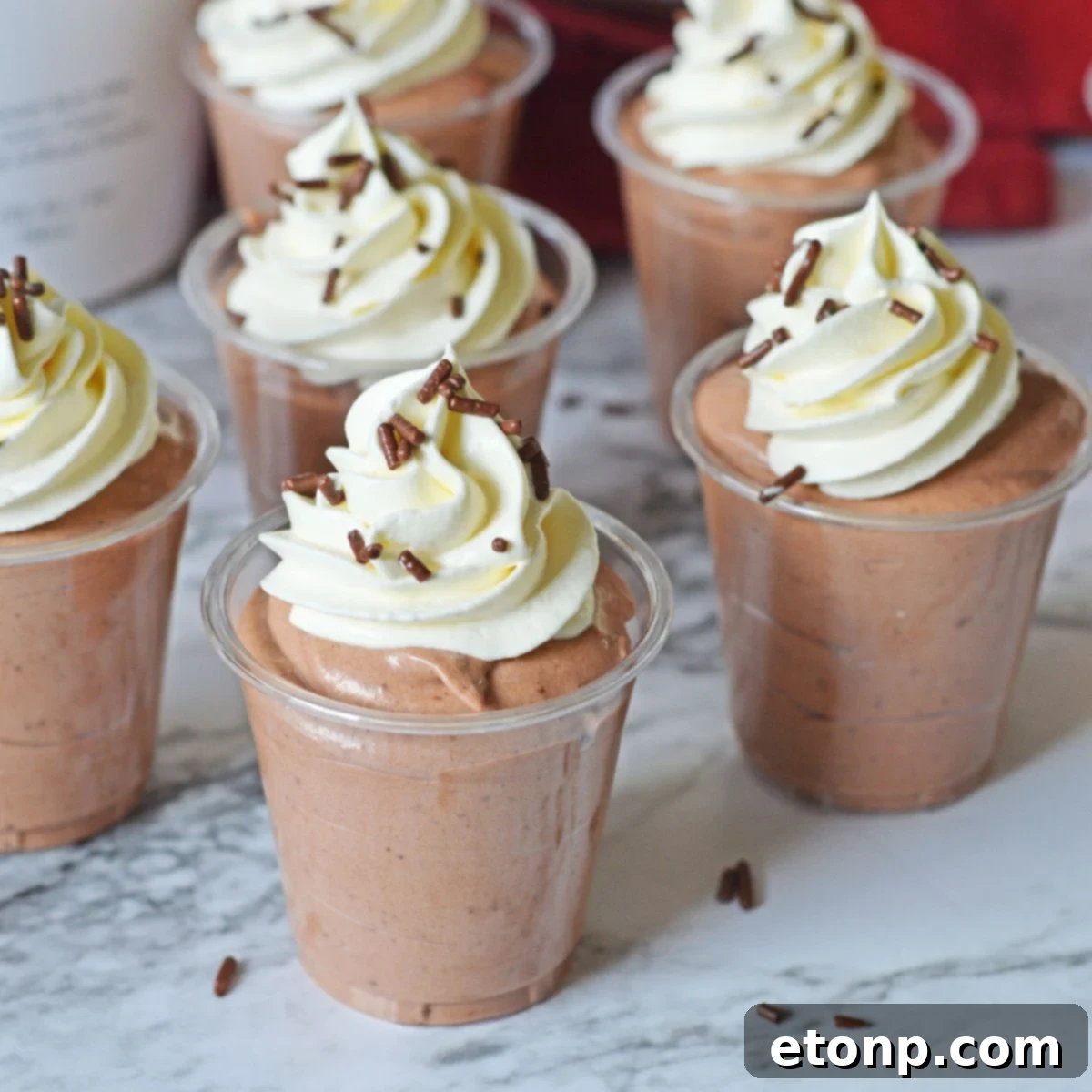 Decadent Chocolate RumChata Pudding Shots 3 Rumchata Pudding Shots on table with whipped cream on top of each one