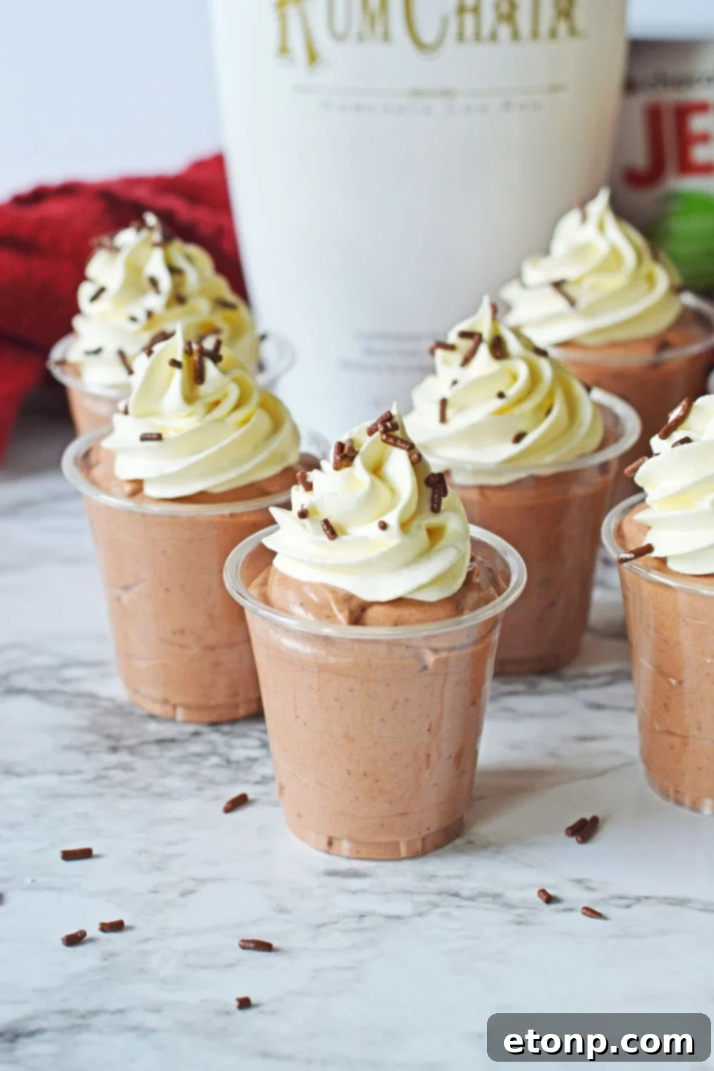 Decadent Chocolate RumChata Pudding Shots 4 Rumchata Pudding Shots on table with RumChata in backround