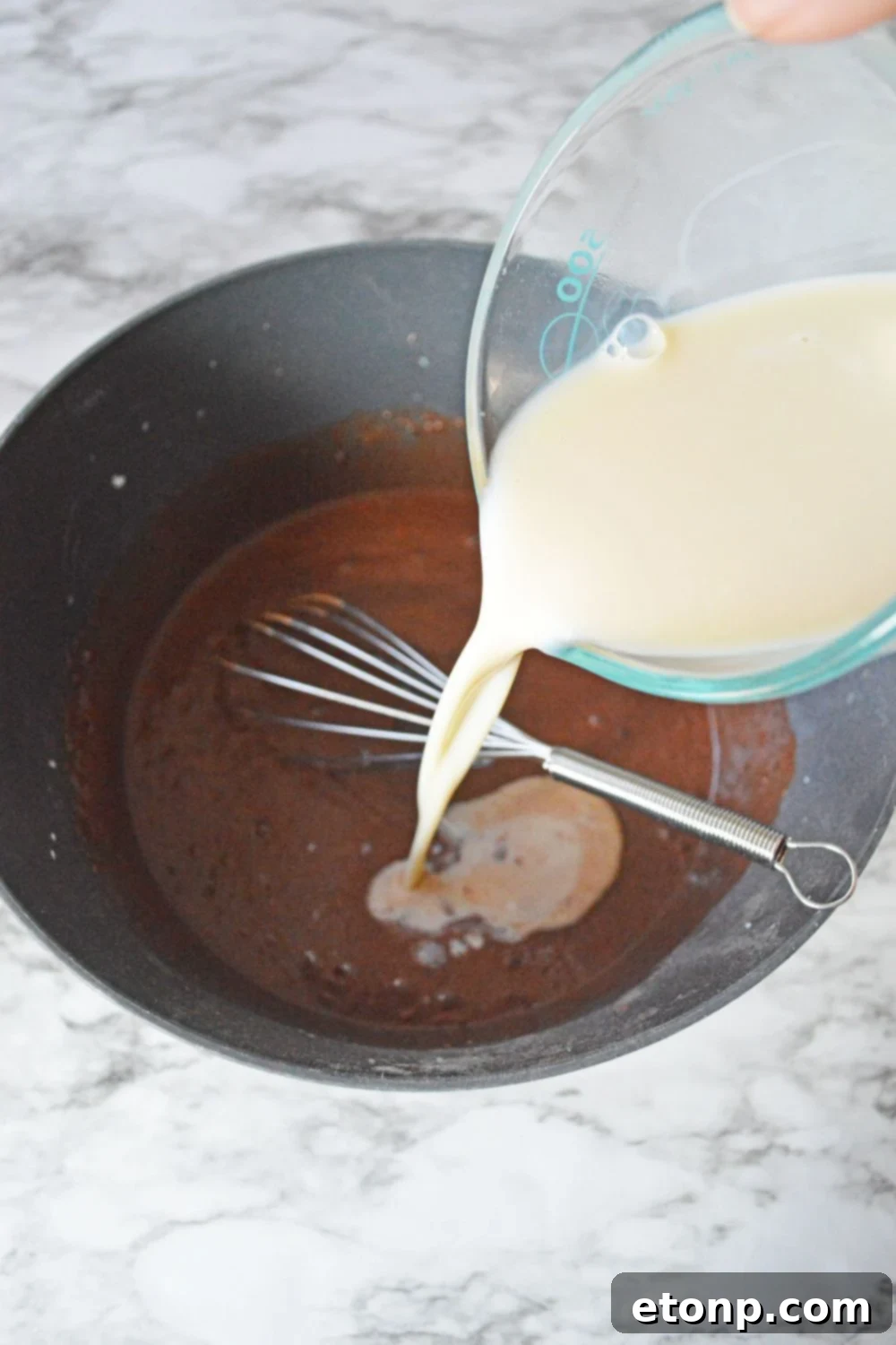 Decadent Chocolate RumChata Pudding Shots 8 milk being poured into chocolate pudding mixture in bowl
