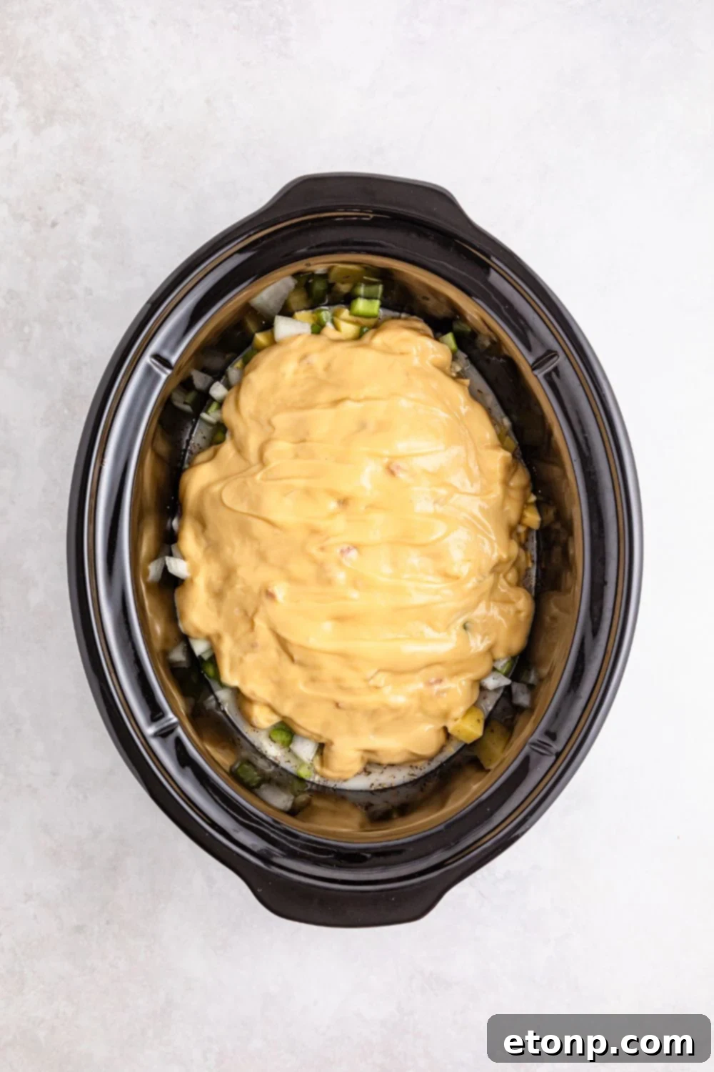 cream of chicken soup poured over veggies in slow cooker on table 