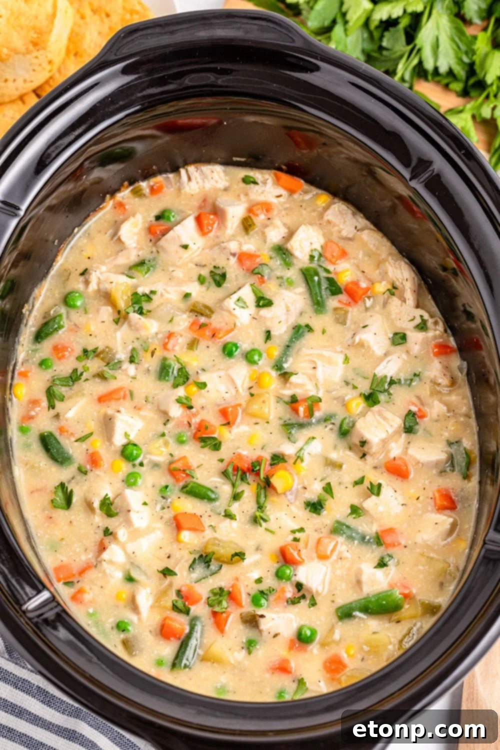 Slow Cooker Chicken Pot Pie in a slow cooker sitting on table with a towel on side 
