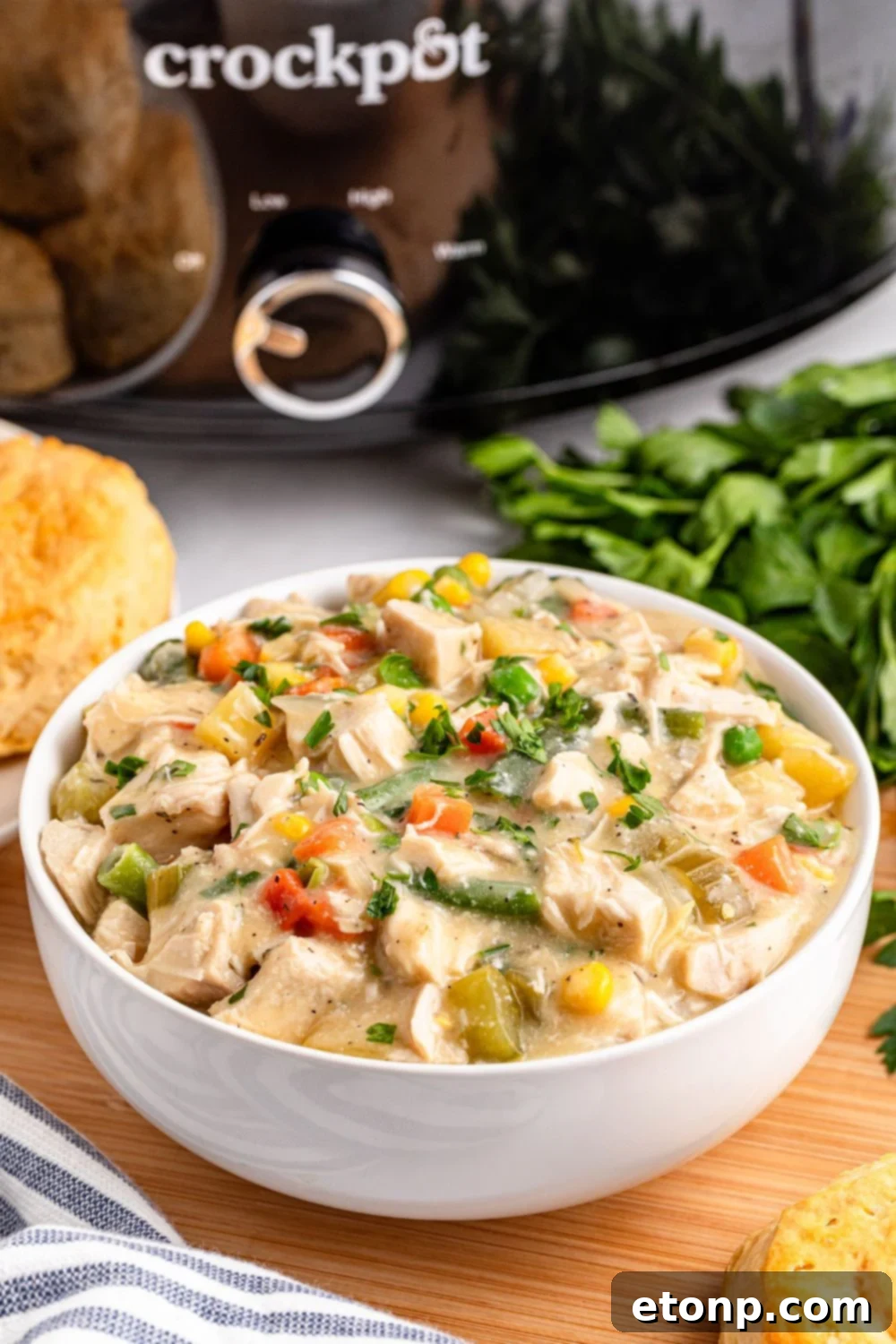 Slow Cooker Chicken Pot Pie in a bowl with a slow cooker behind it on table 