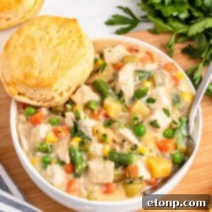 Slow Cooker Chicken Pot Pie in a bowl with a biscuit on side of bowl