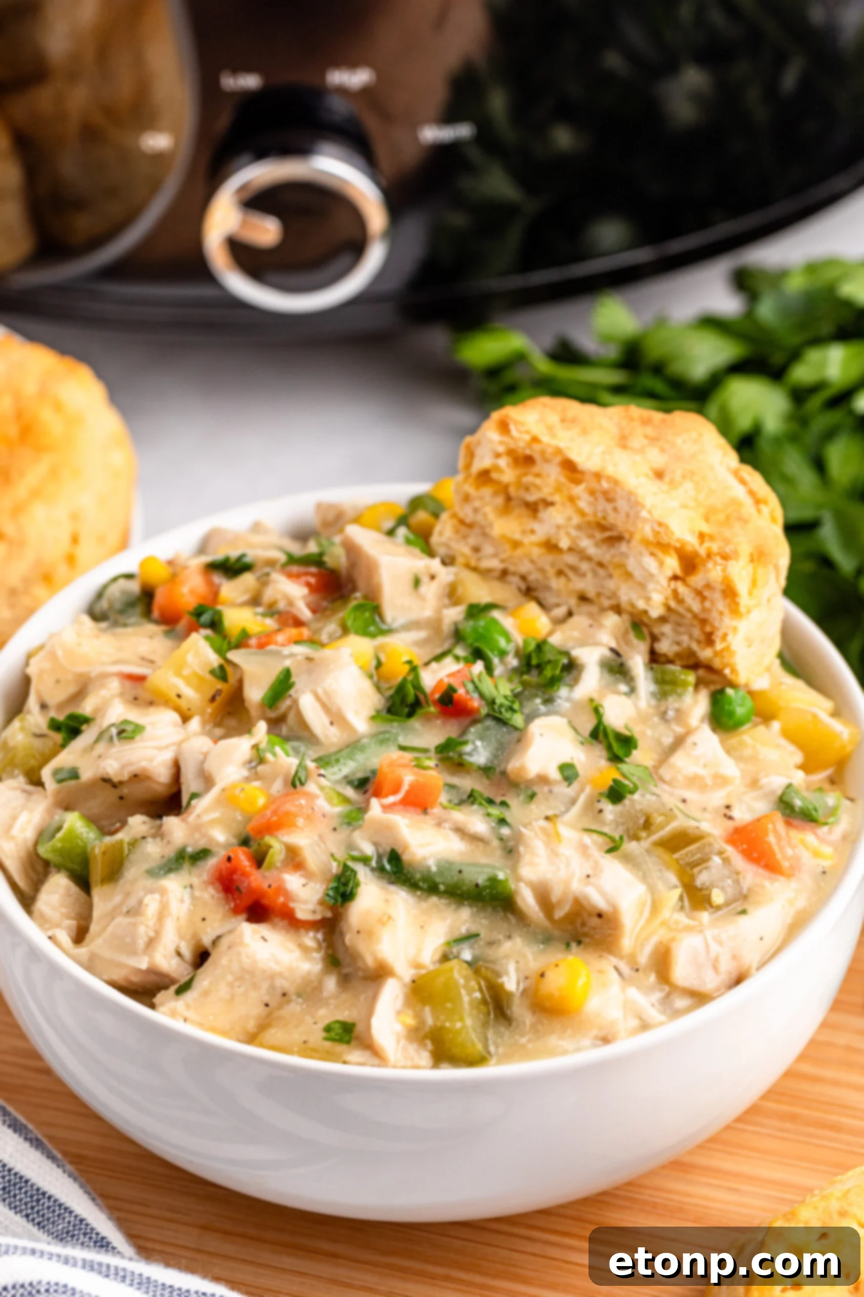 white bowl filled with Slow Cooker Chicken Pot Pie with a biscuit on the side