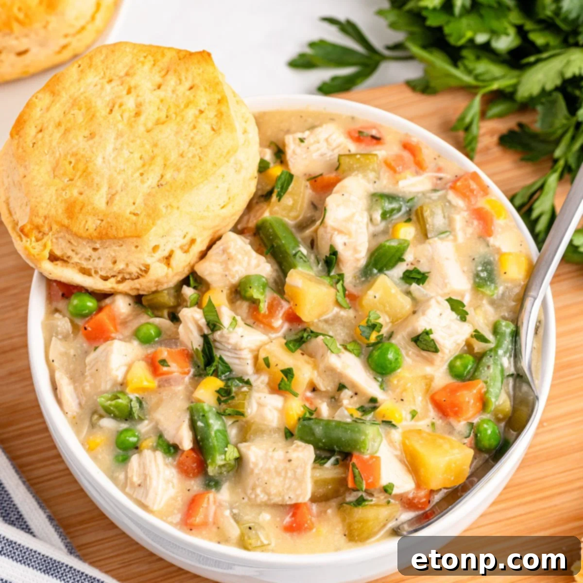Slow Cooker Chicken Pot Pie in a bowl with a biscuit on side of bowl 
