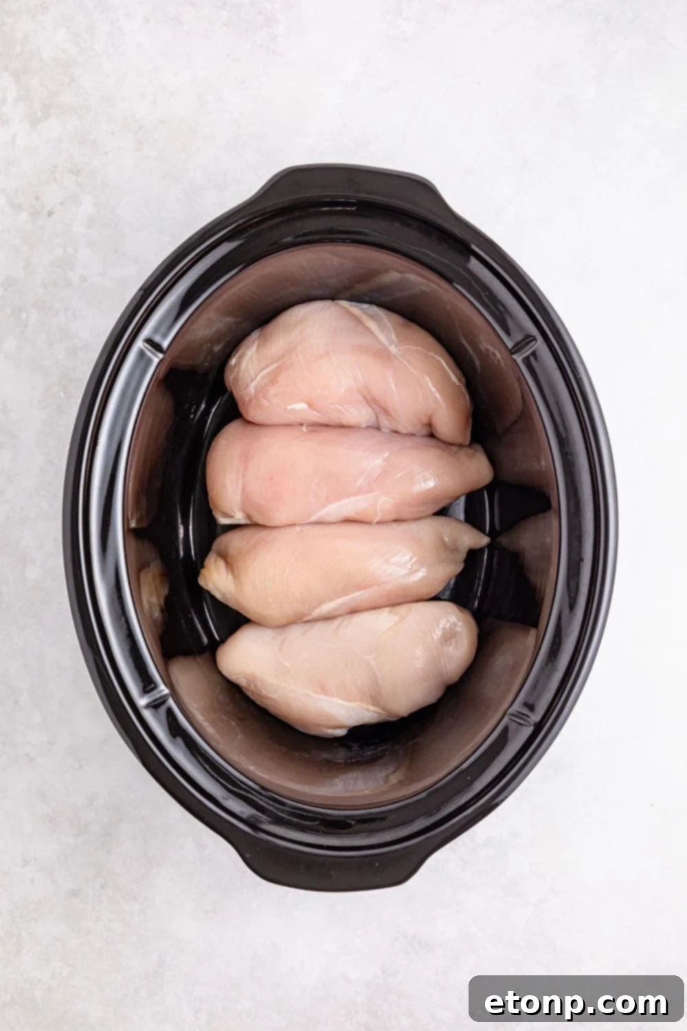 raw chicken breast in slow cooker on table 