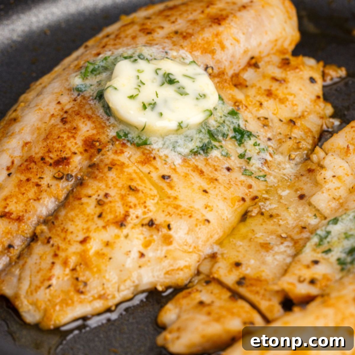 Pan Fried Tilapia in skillet with lemon butter on top