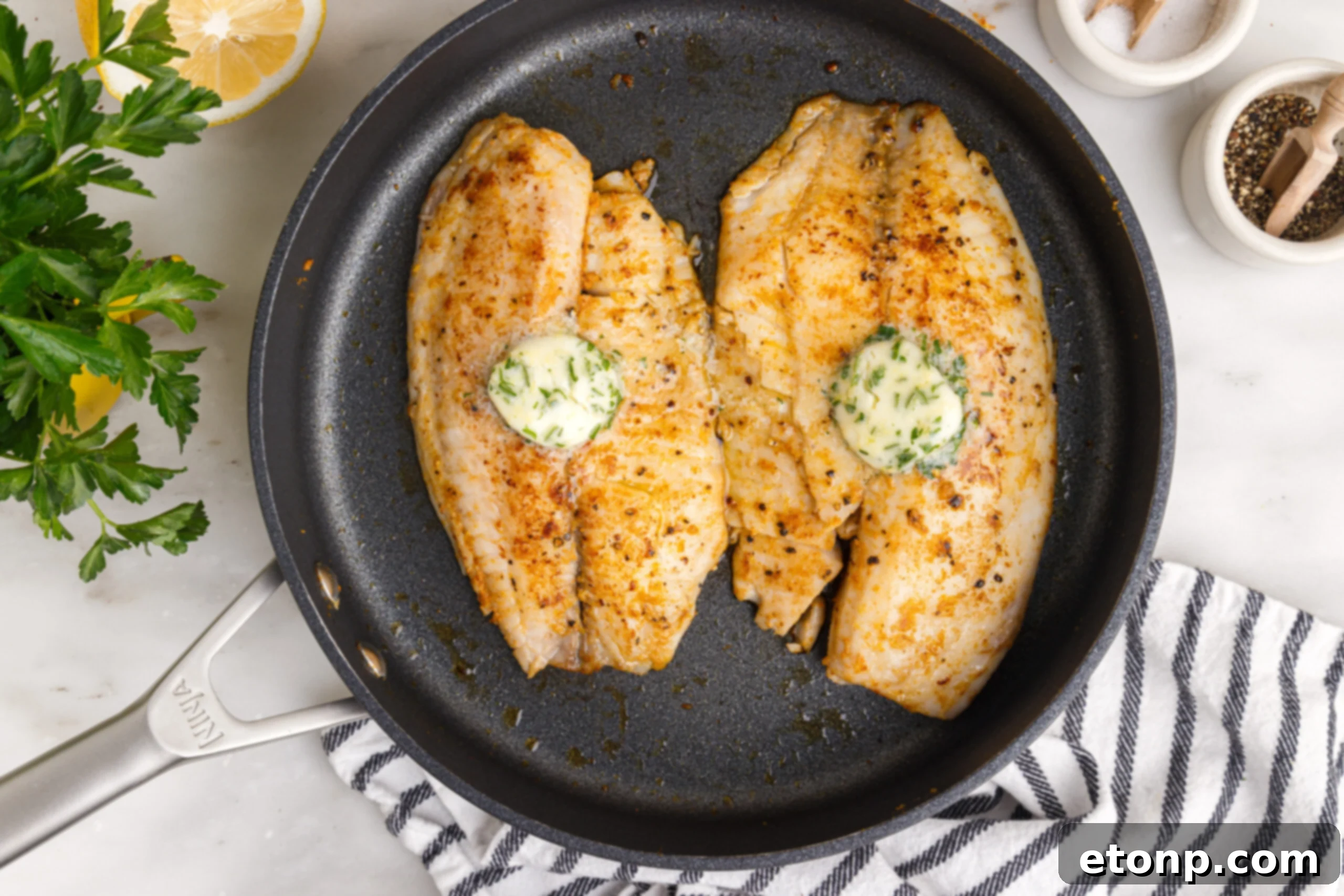 overhead shot of the Pan Fried Tilapia in a skillet up close topped with butter