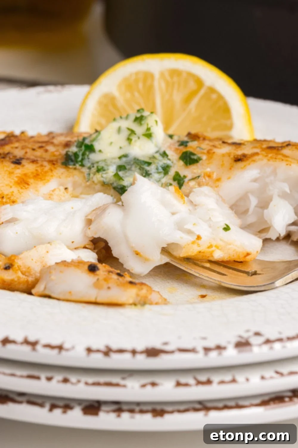 Pan Fried Tilapia on plate with a lemon wedge on side