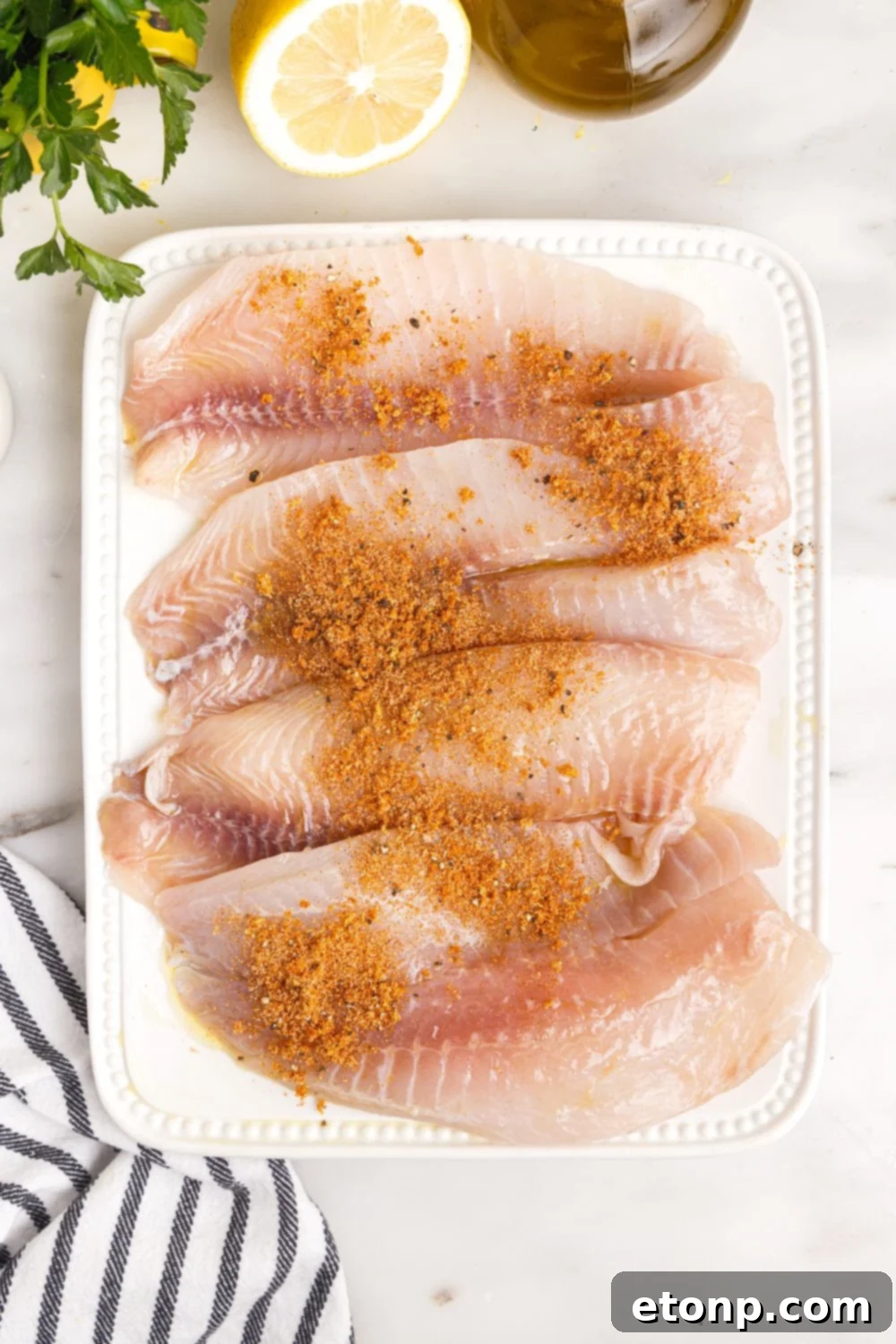 tilapia on cutting board with seasoning on it